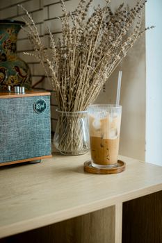 A refreshing iced coffee next to rustic decor and retro speaker on a wooden shelf.
