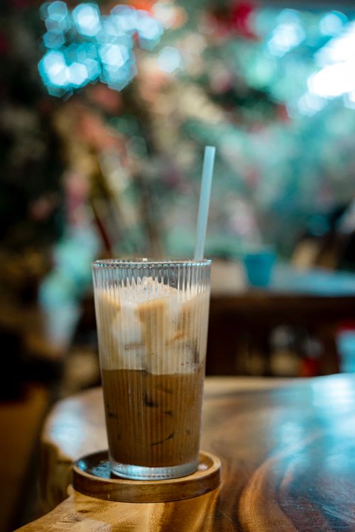 Free Chilled iced coffee on a wooden table in a cozy cafe with a colorful bokeh backdrop. Stock Photo
