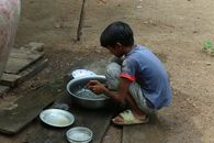A young boy washing dishes outside in Mondulkiri Province, Cambodia.