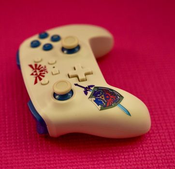 Close-up of a gaming controller with a unique design on a vibrant pink surface.