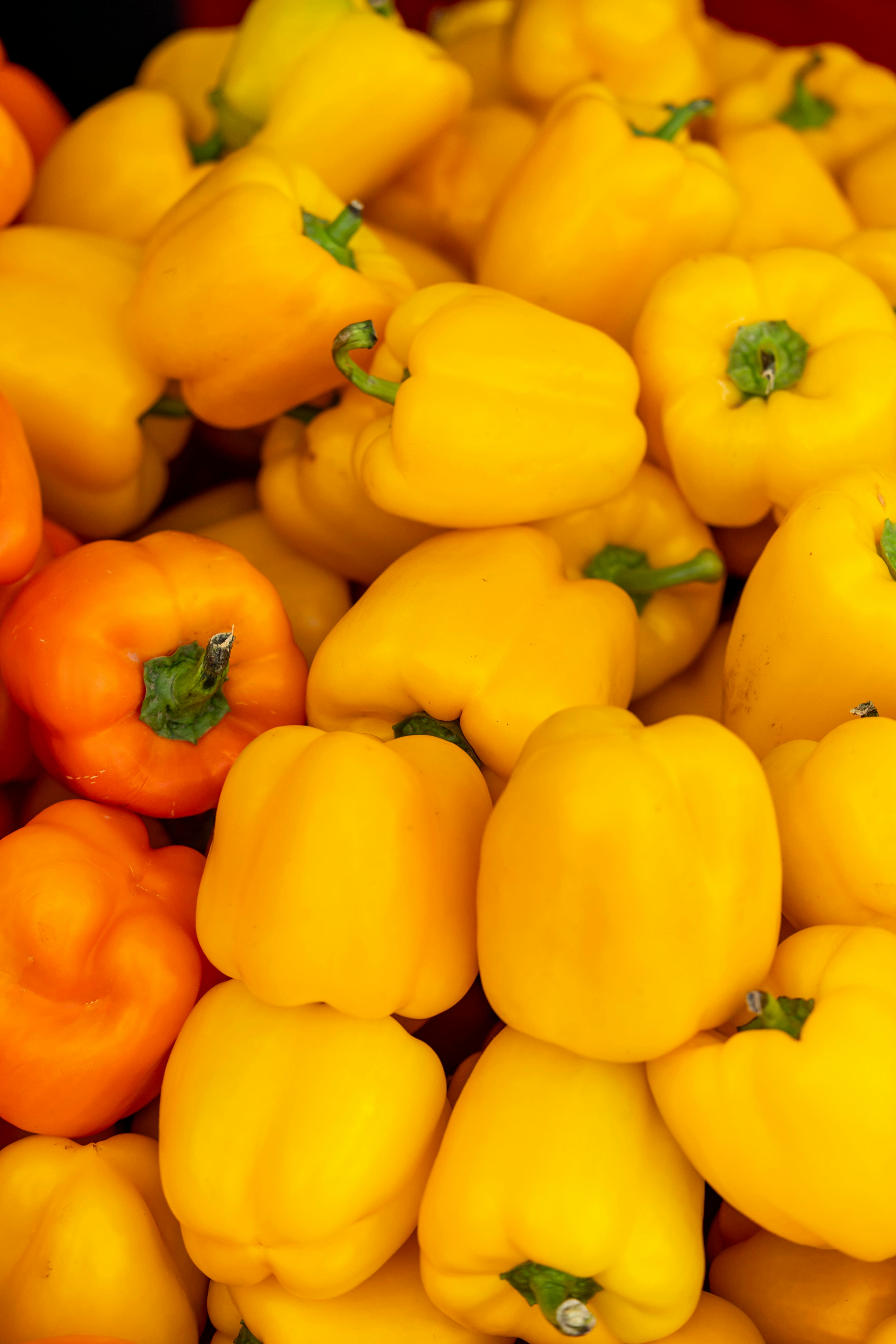 Fresh yellow and orange bell peppers stacked together, showcasing vibrant colors.
