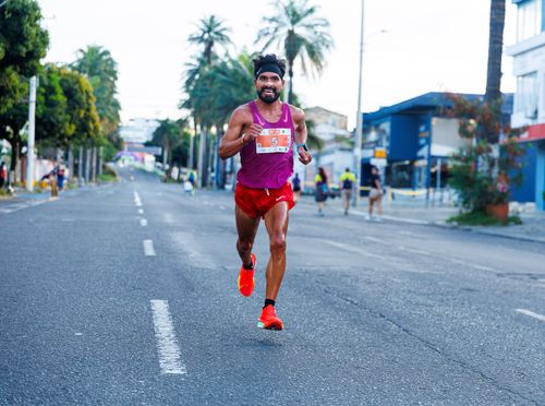 Free Athlete in vibrant attire competing in a city marathon on a sunny day. Stock Photo