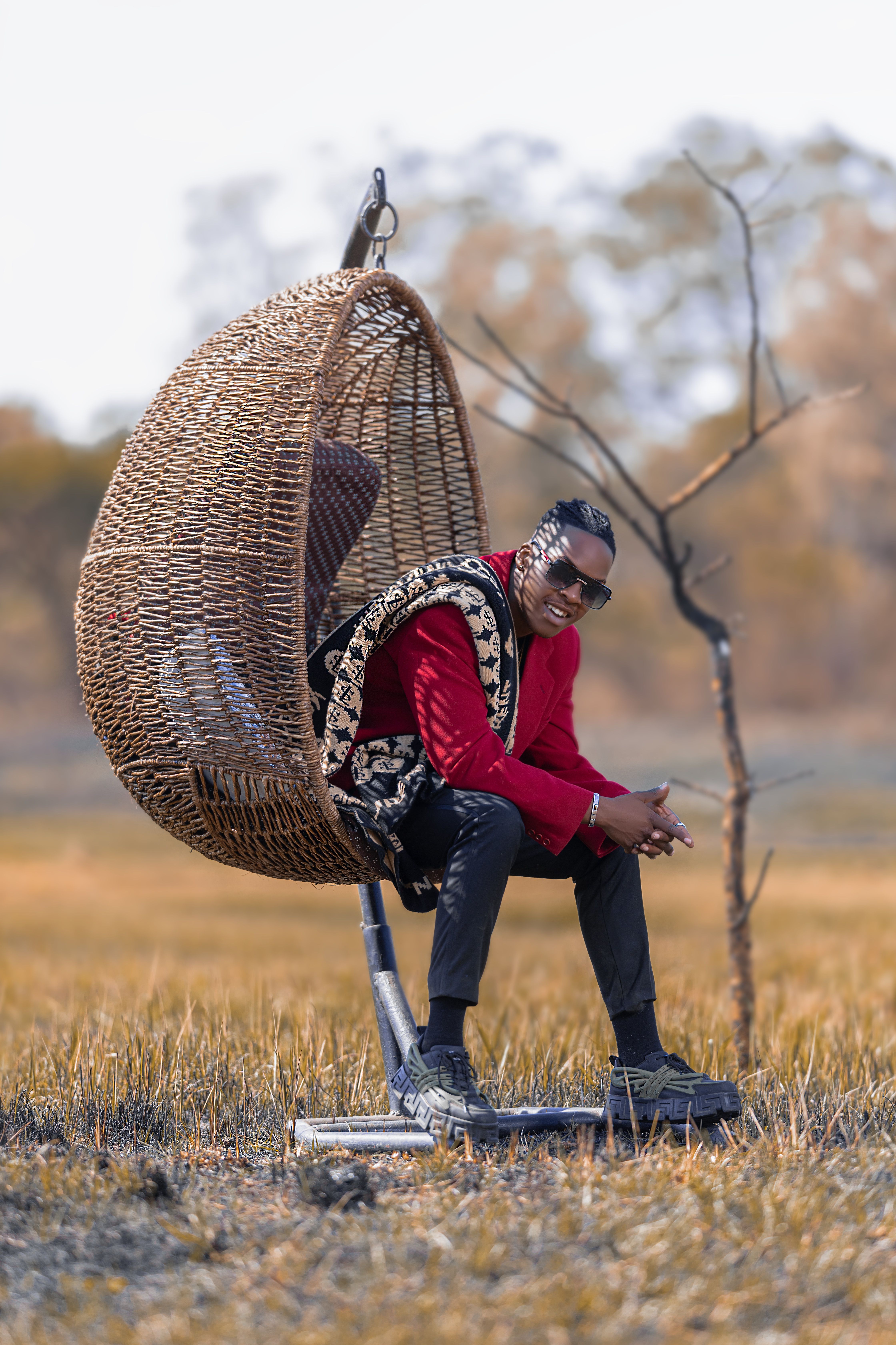 Fashionable man in a wicker chair outdoors, a blend of nature and style.