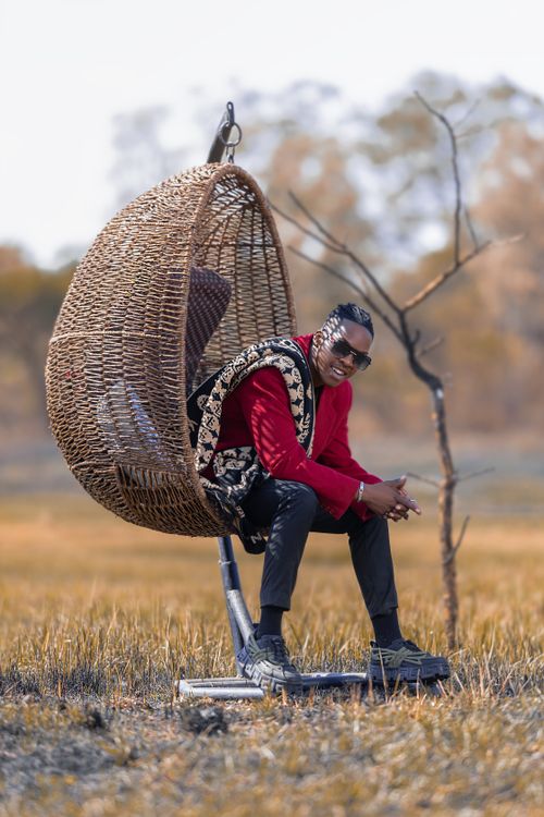 Free Fashionable man in a wicker chair outdoors, a blend of nature and style. Stock Photo