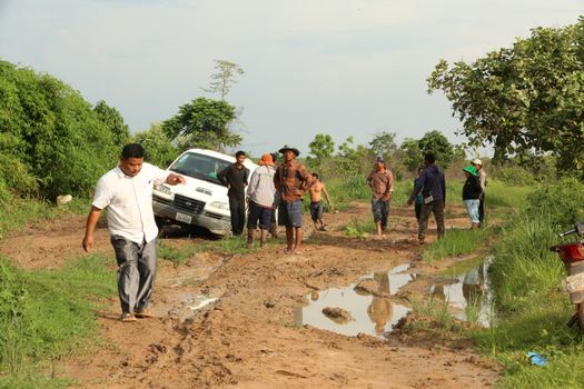 A group of people dealing with a muddy road situation in Mondulkiri, Cambodia.