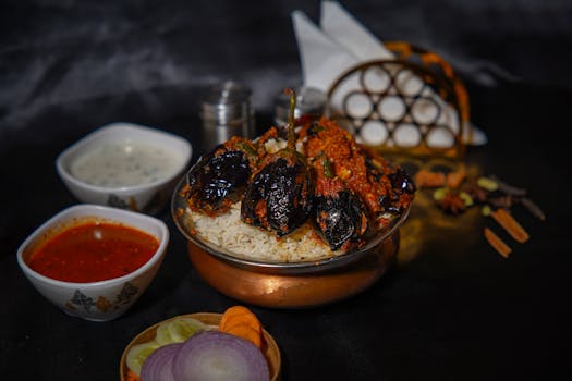 Aromatic biryani served with flavorful sides and spices on a dark background.
