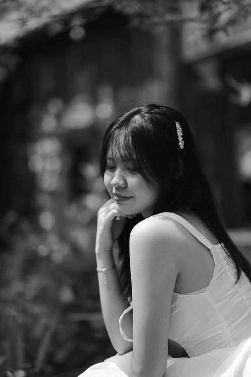 Free A serene black and white portrait of a young woman smiling in natural light. Stock Photo