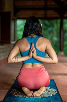 Woman in yoga pose on mat outdoors, focusing on mindfulness and meditation.
