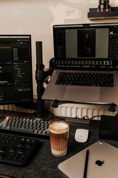 A cozy home office setup in London with a latte, multiple monitors, and tech gadgets.