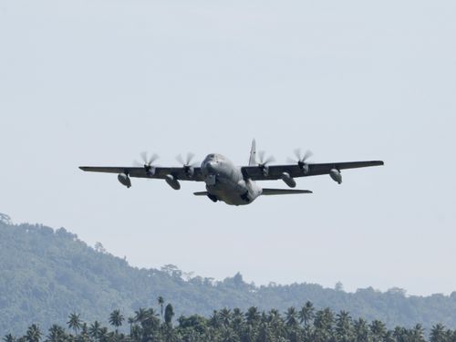 Free C-130 Hercules aircraft in flight over lush landscapes in Sulawesi, Indonesia. Stock Photo