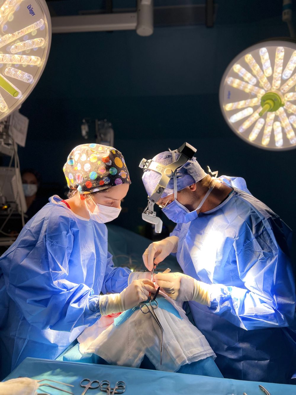 Two surgeons performing an operation under surgical lights in a sterile operating room