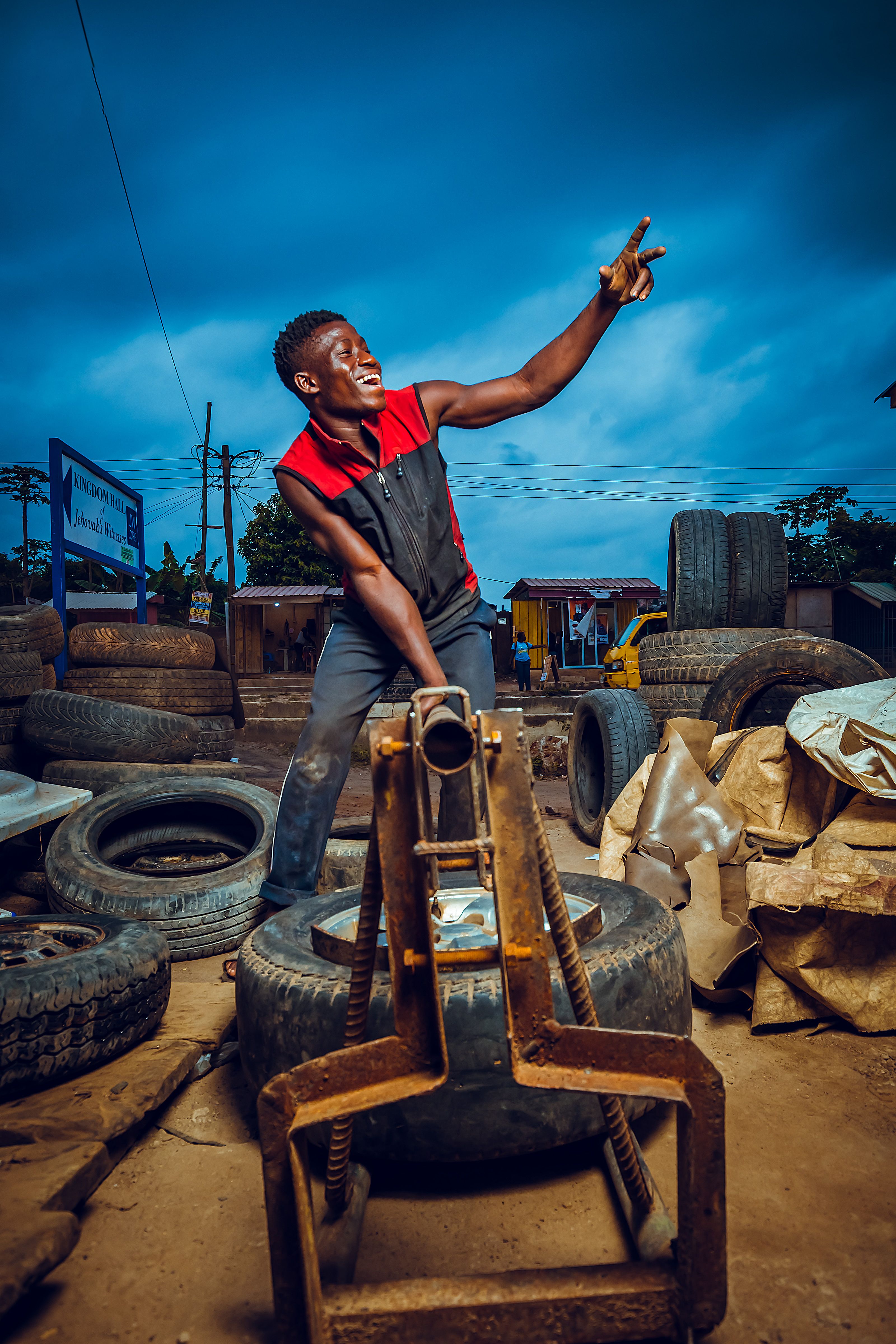 Cheerful African mechanic posing energetically in an outdoor auto repair shop in Accra, Ghana.