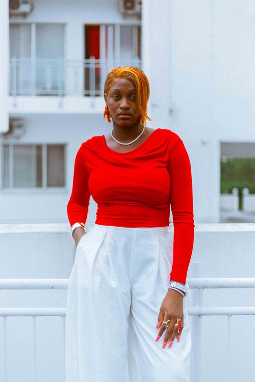 Free Fashionable woman in red top and white pants posing outdoors in urban setting. Stock Photo