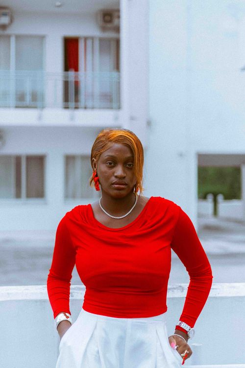 Free Stylish woman in red top posing outside a modern building. Stock Photo