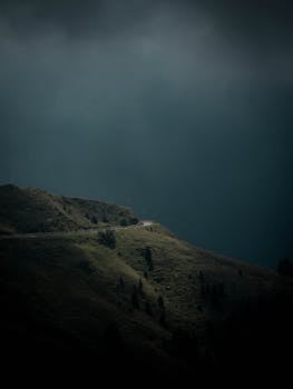 在黑暗、戏剧性的天空下，蜿蜒的山路展现出令人惊叹的自然景观