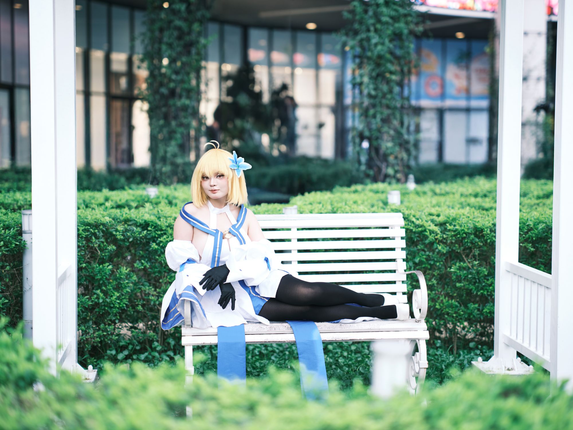 Cosplayer in Blue Costume Relaxing on Garden Bench · Free Stock Photo