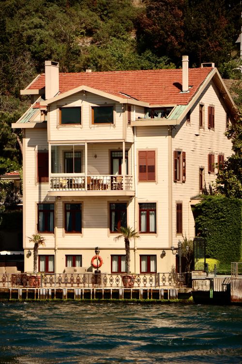 Free Charming house by the water, featuring red roof and lush surroundings. Stock Photo