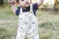 Cute baby with parents' support taking steps on a sunny day in the park.