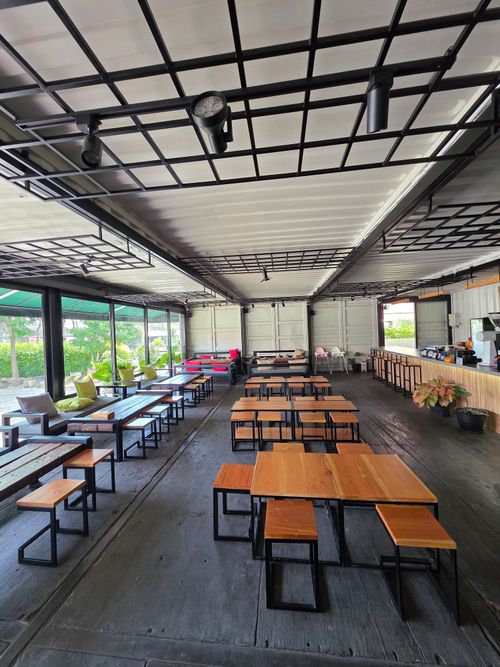 Free Spacious outdoor cafe with sleek wooden furniture, ideal for social gatherings. Stock Photo