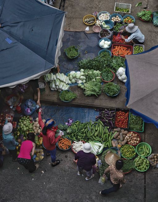 Colorful aerial shot of a bustling street market with diverse fresh vegetables on display.