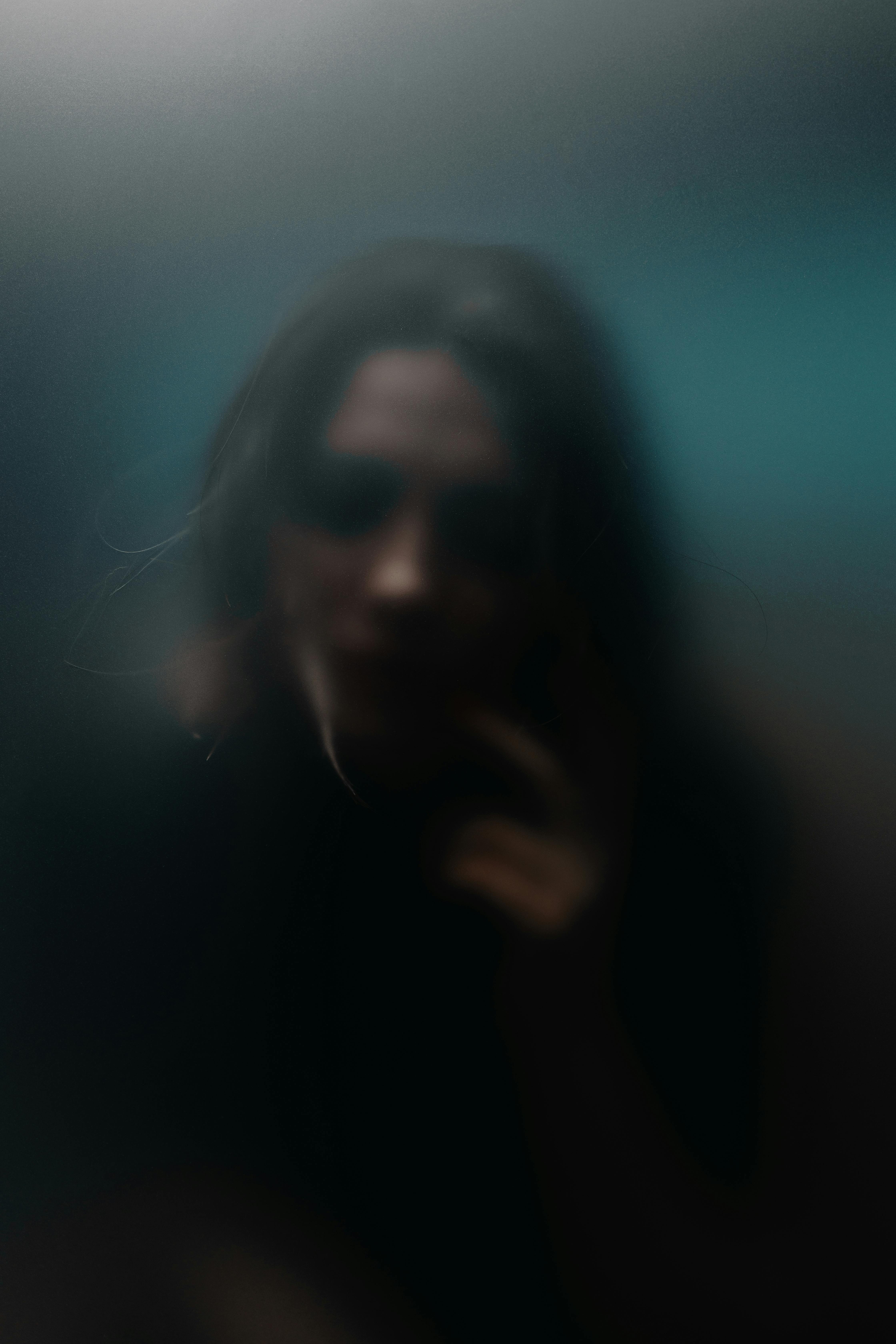 A mysterious blurred portrait with a moody and dramatic atmosphere.