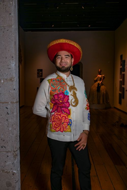 Free Portrait of a man in colorful Mexican attire inside an art gallery. Stock Photo
