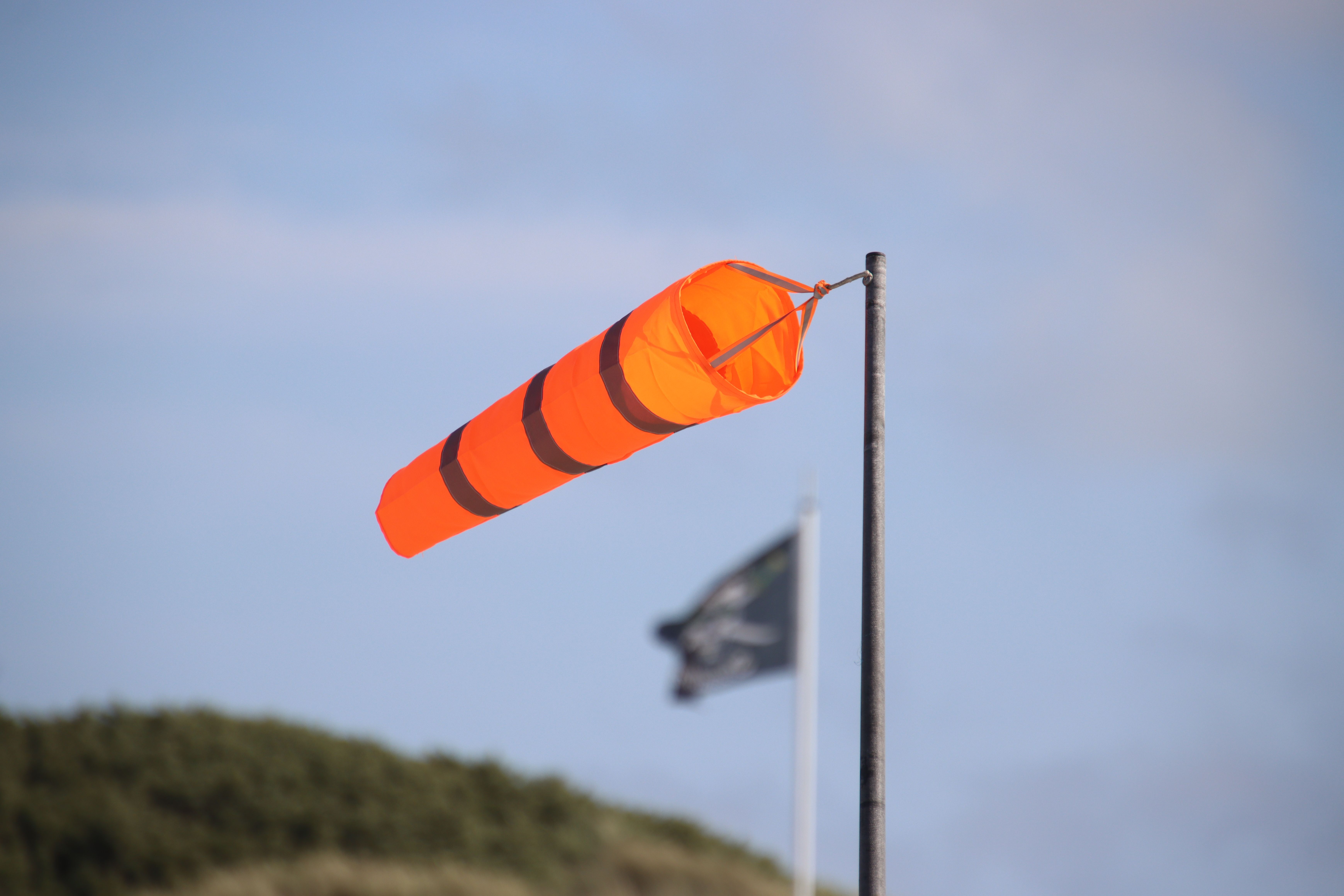 Bright orange windsock indicating wind direction against clear sky background.