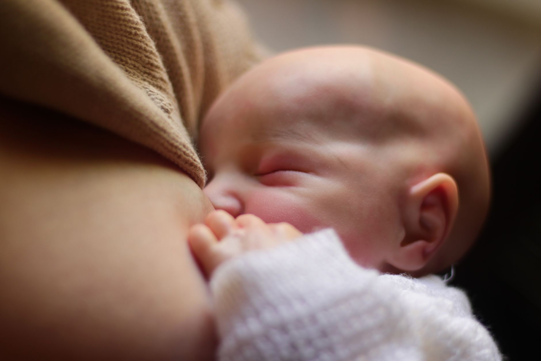 A newborn baby peacefully breastfeeding, capturing an intimate moment of mother-child bonding.
