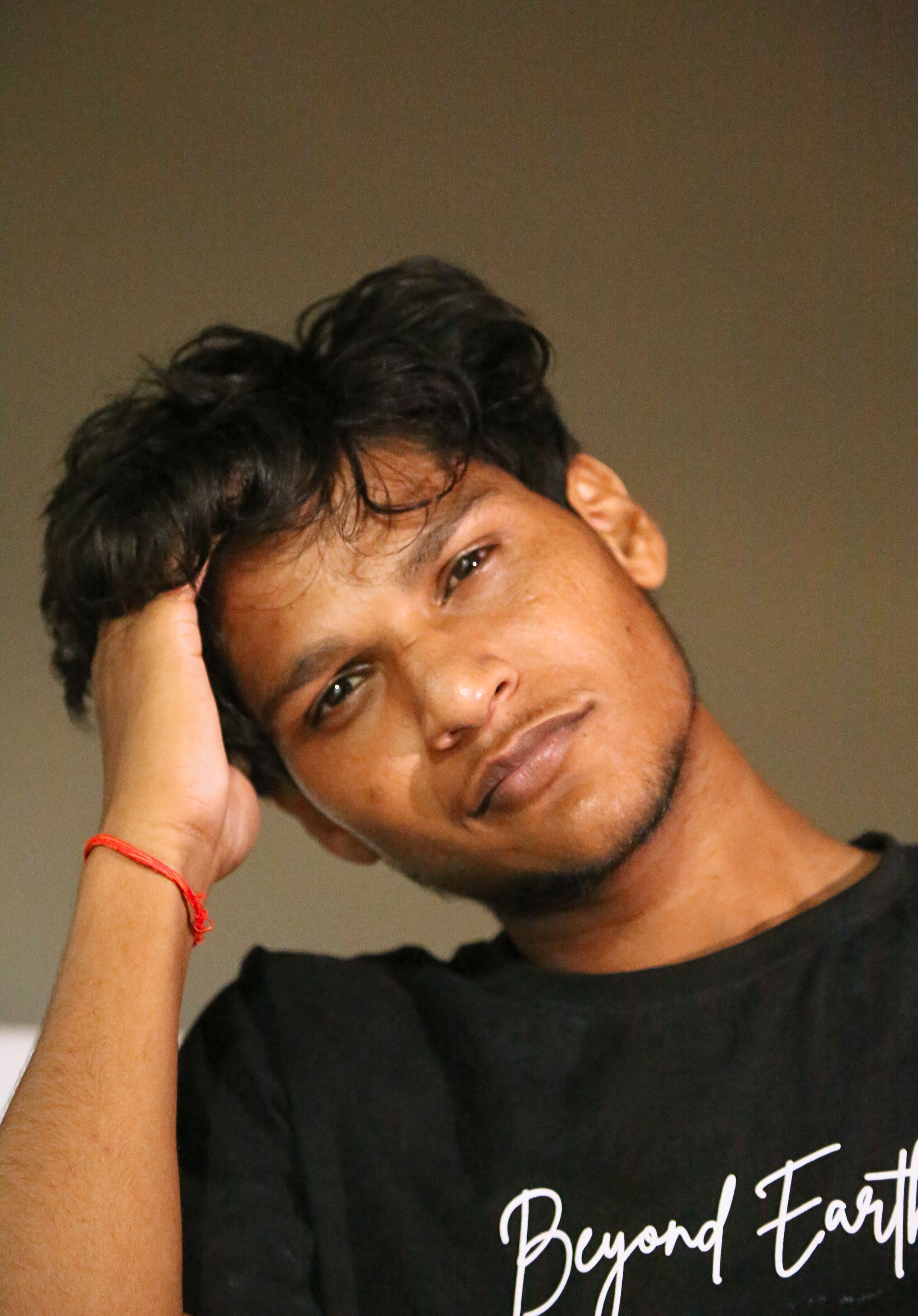Portrait of a young man indoors, lost in thought, with relaxed expression.