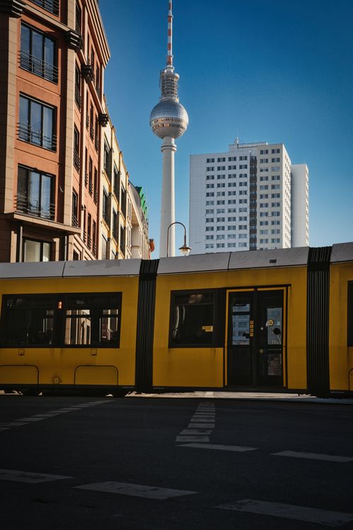 Free Captured in Berlin, a yellow tram passes with the iconic Fernsehturm in the background. Stock Photo