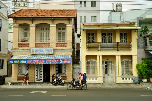 Free Bicyclists and pedestrians pass colonial style buildings on a Vietnamese street. Stock Photo
