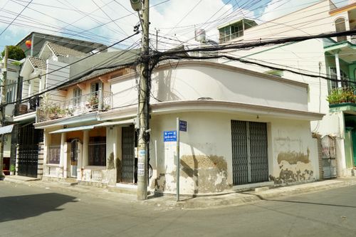Free A corner residential building with weathered walls and overhead wires in a sunny urban environment. Stock Photo