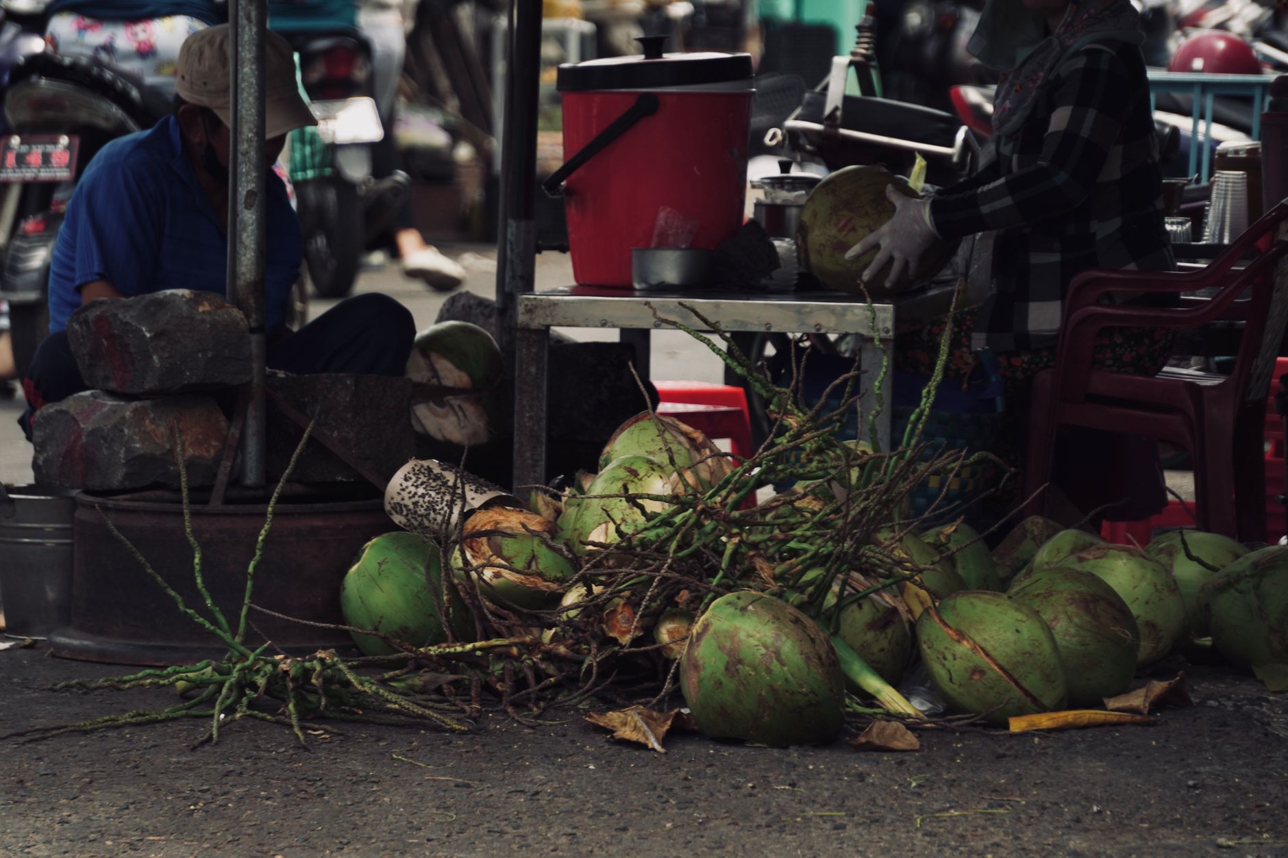 Street vendor preparing fresh coconuts at an outdoor market with vibrant display.
