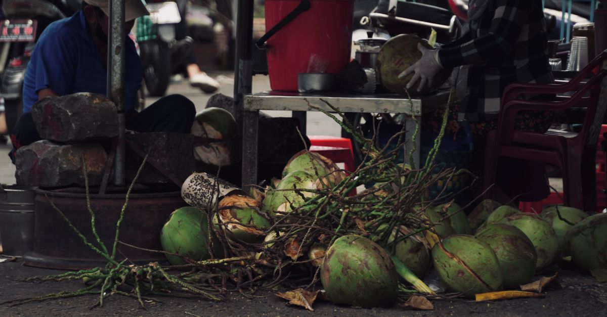 Street vendor preparing fresh coconuts at an outdoor market with vibrant display. - Evidence evidence guide for coconut water muscle cramps randomized trial