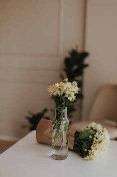 Chic indoor setting featuring white and yellow flowers in a glass vase with soft lighting.
