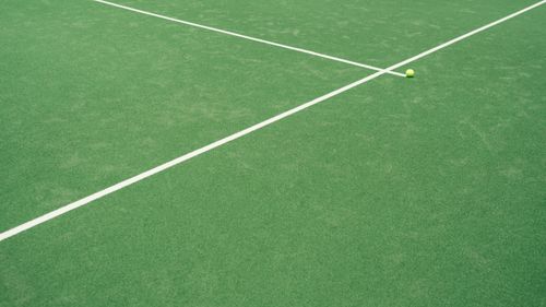 Free A tennis ball on a green court displaying crisp white lines under daylight. Stock Photo