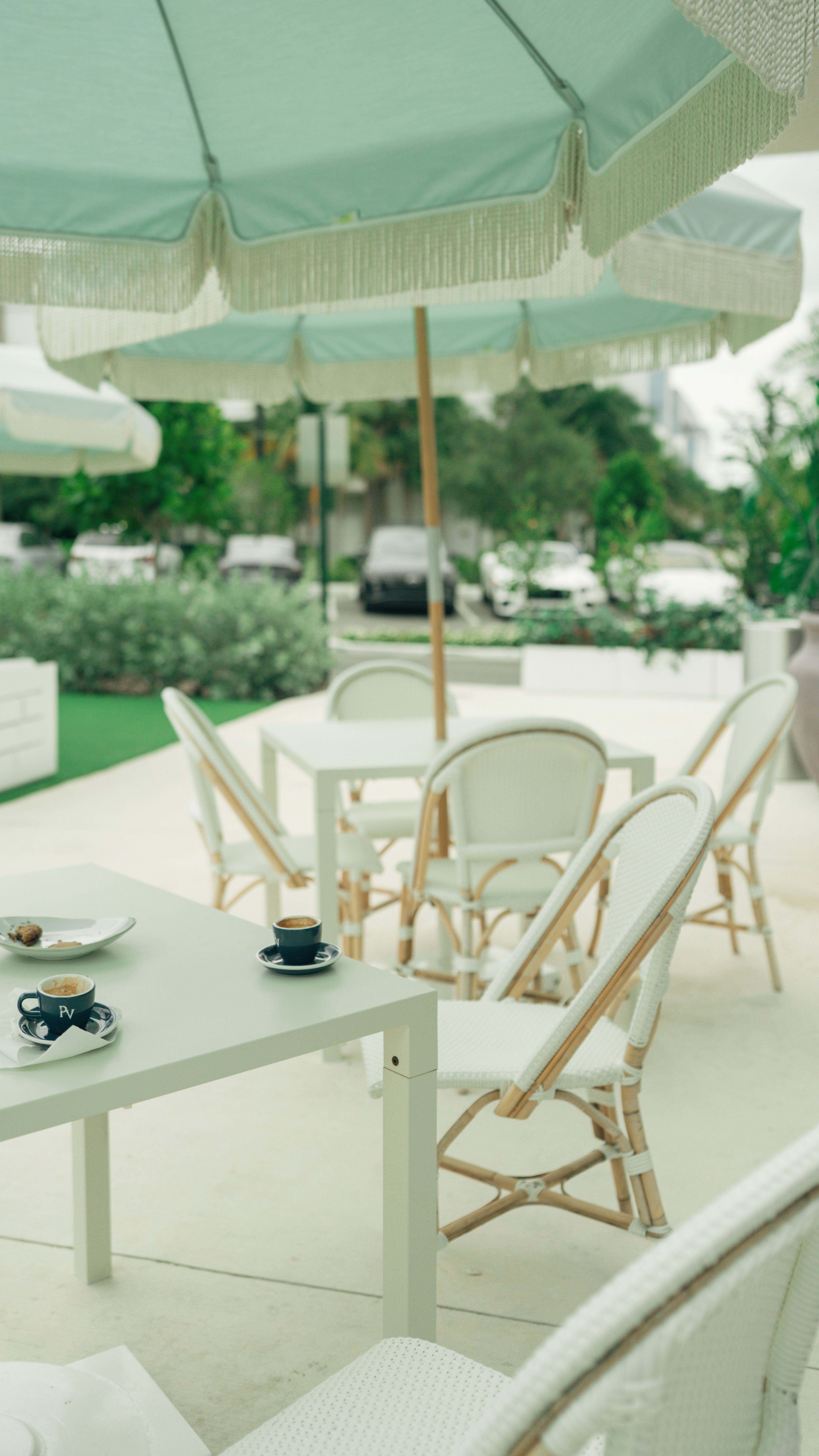 Stylish outdoor cafe setting with pastel parasols and wicker chairs on a sunny day.