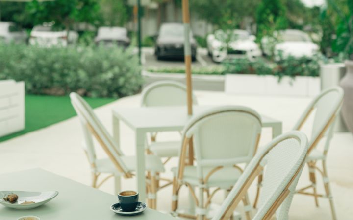 Stylish outdoor cafe setting with pastel parasols and wicker chairs on a sunny day.