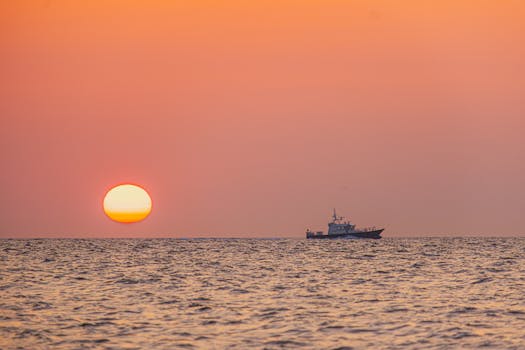 Tranquil sunset over the sea in Middelkerke, Belgium, with a fishing boat silhouetted on the horizon.