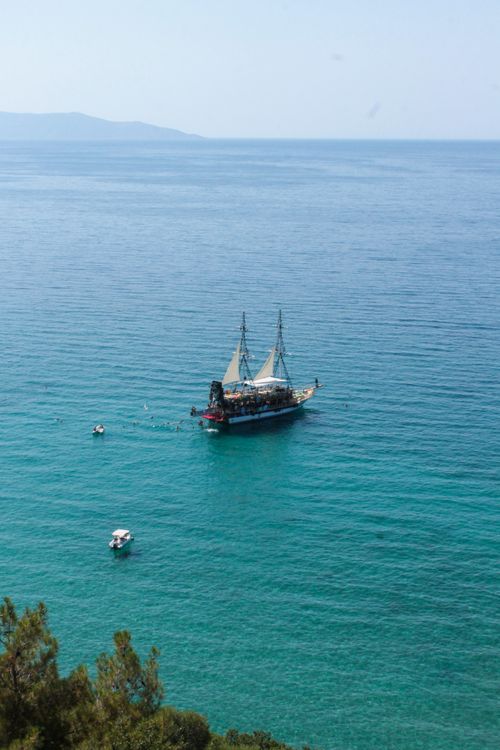 Free Pirate ship cruising on crystal clear blue sea surrounded by smaller boats. Stock Photo