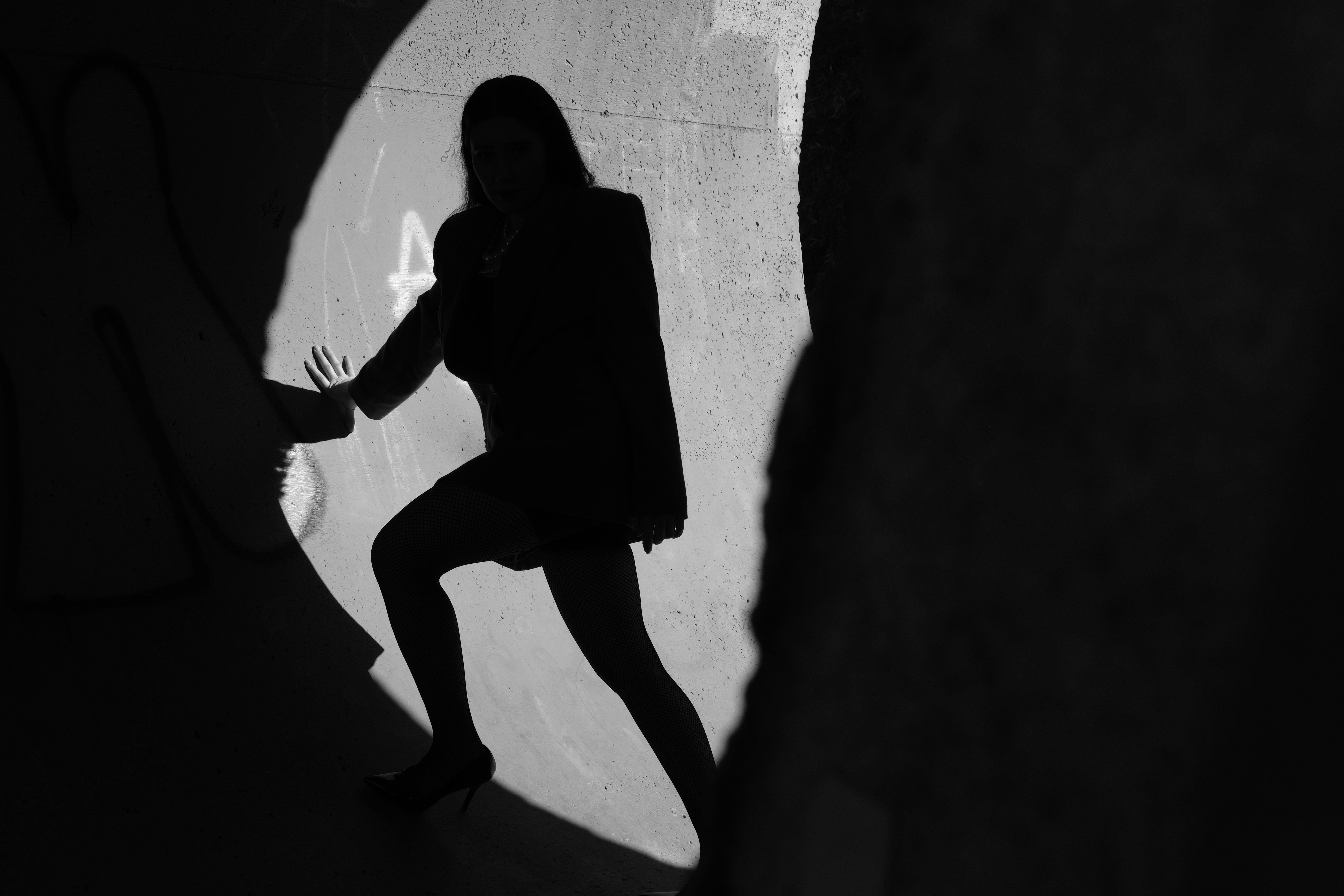 grátis Silhueta artística de uma mulher em um túnel, destacada por sombras dramáticas e luz brilhante. Foto profissional
