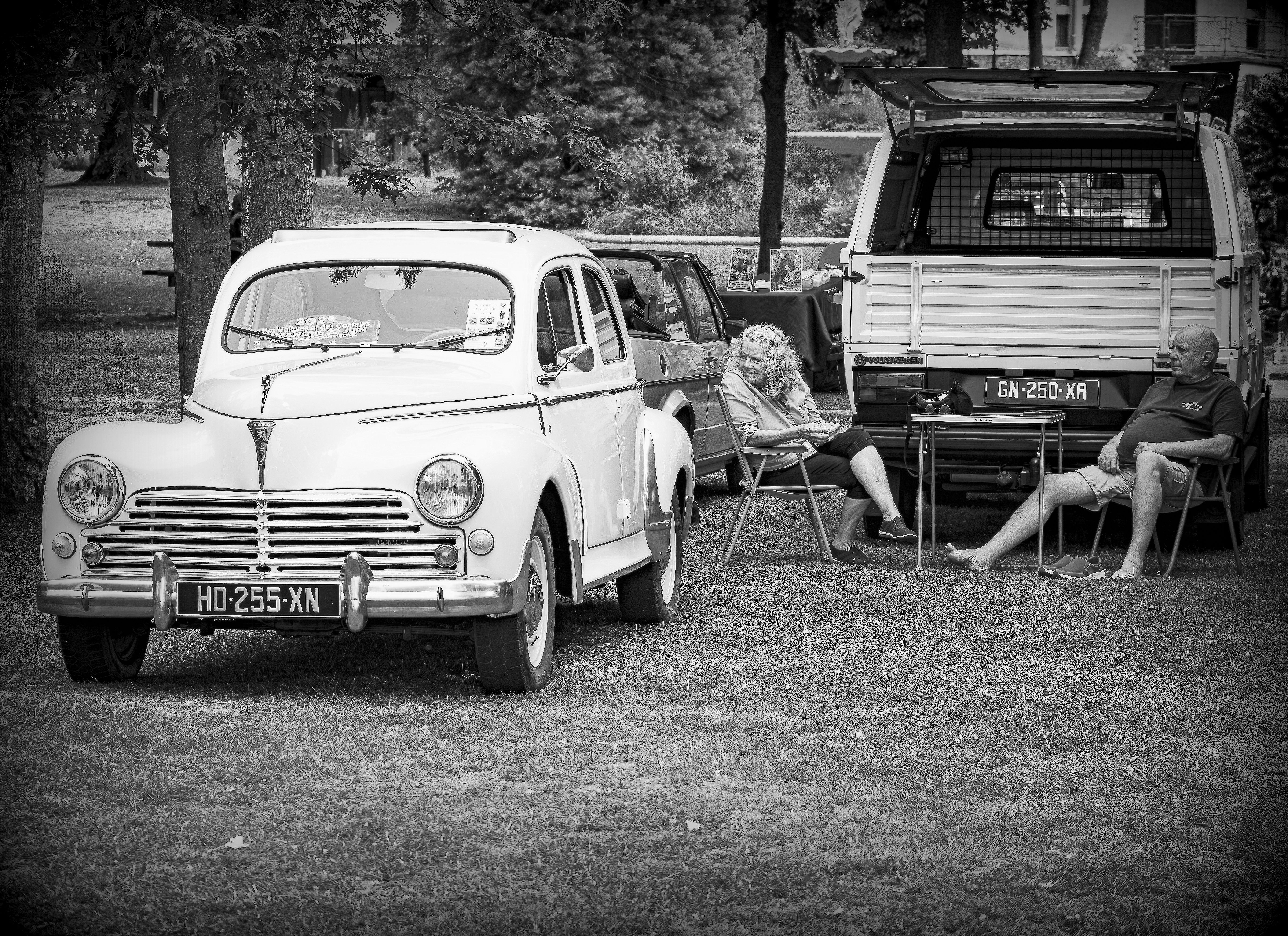 Vintage car and people relaxing in a park in black and white.
