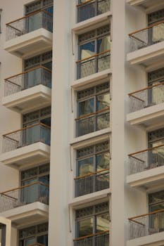 Modern apartment building with glass balconies, sleek architectural design.
