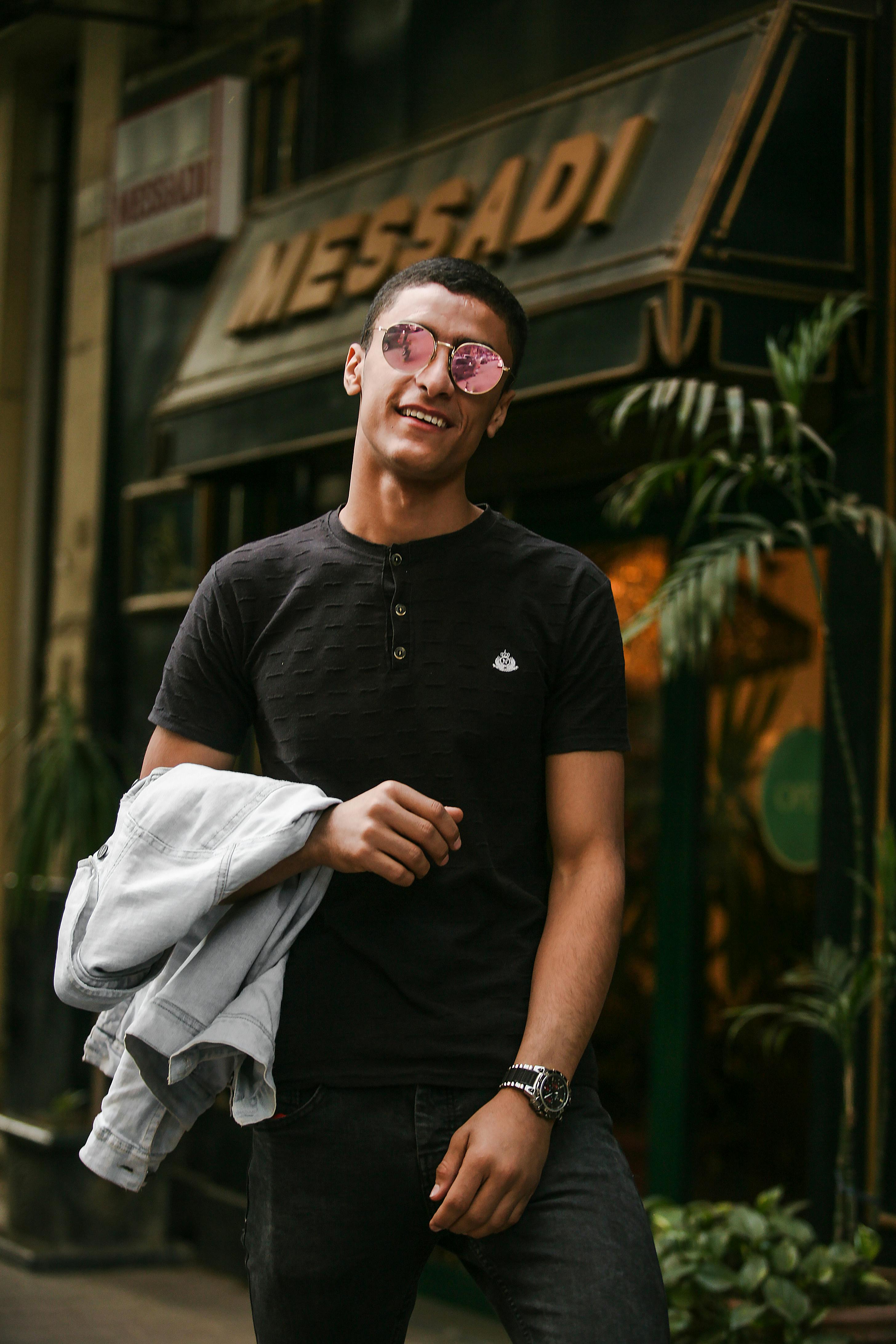 一位穿着休闲装的时尚男士在户外自信地摆出姿势，散发着魅力与时尚气息