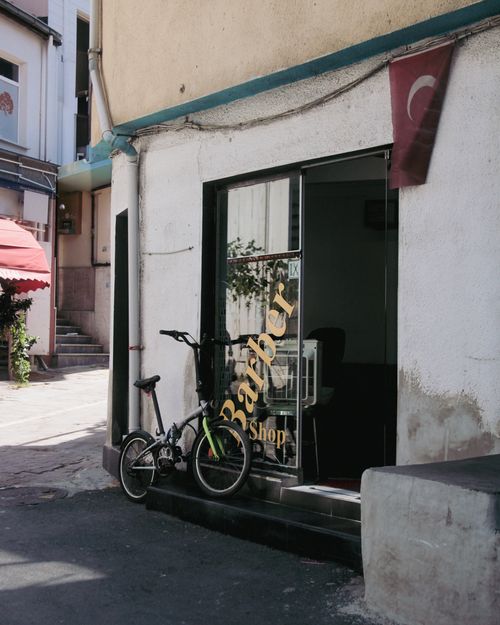 Free Charming barber shop entrance in a sunlit Turkish alley, featuring a bicycle parked outside. Stock Photo