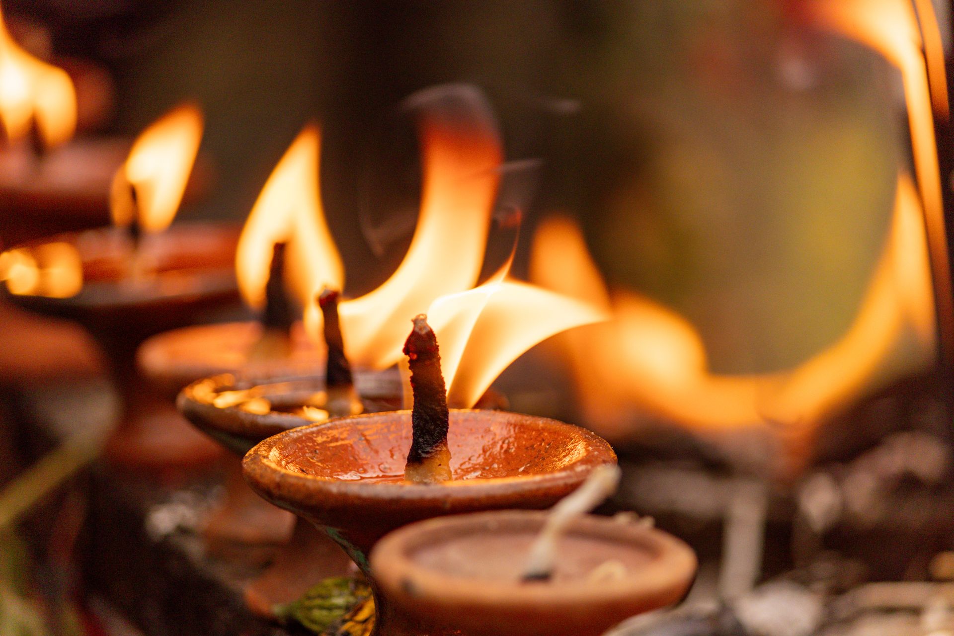 Close-up view of traditional clay oil lamps with flickering flames creating a warm ambiance.
