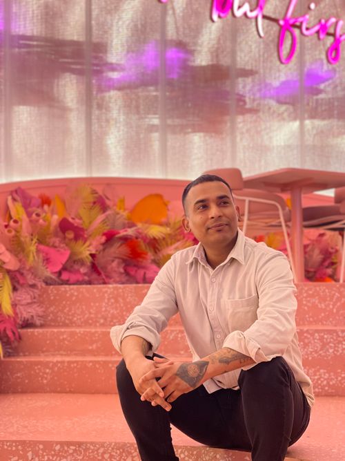 Free Casual portrait of a person sitting indoors with vibrant pink decor and ambient light. Stock Photo