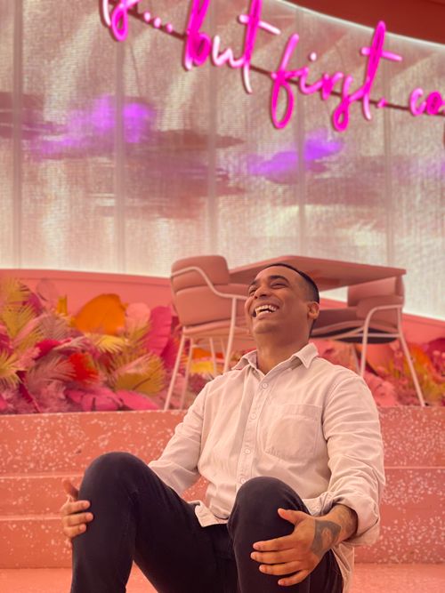 Free A man in a pink-themed café, laughing and enjoying a relaxed moment. Stock Photo
