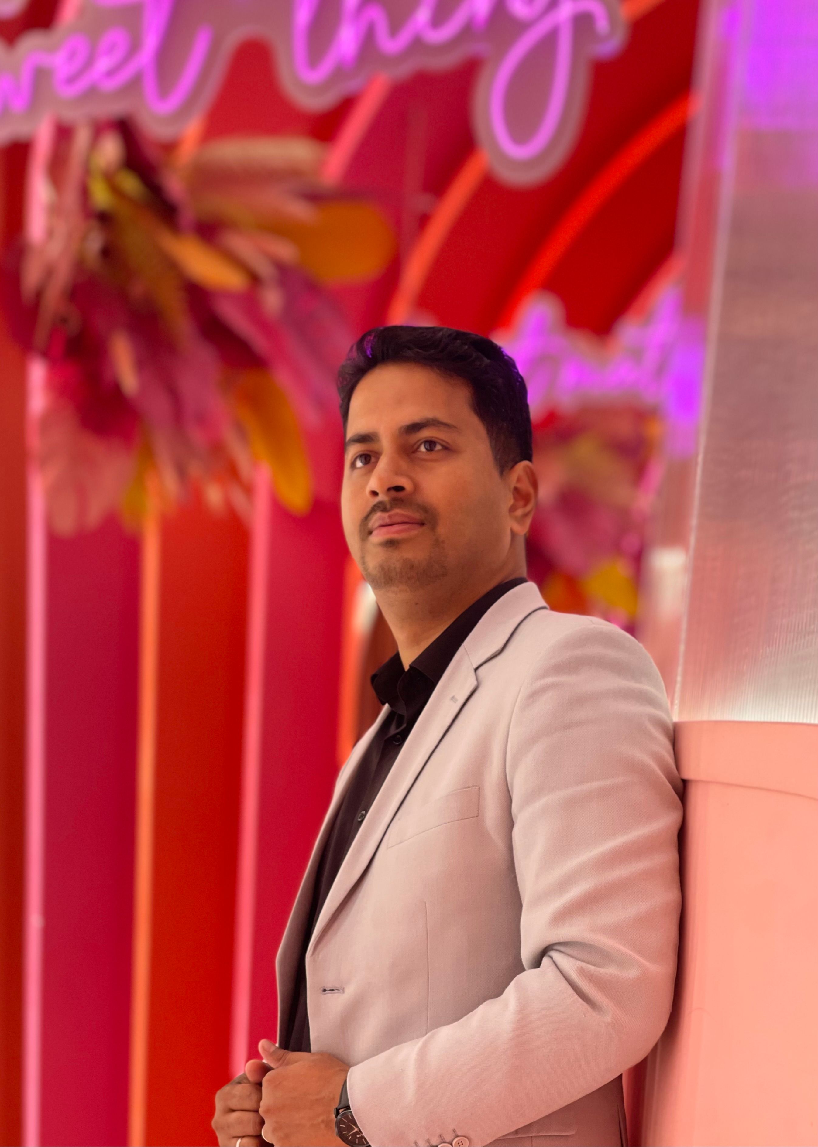 Portrait of a confident man in a blazer with vibrant pink background.
