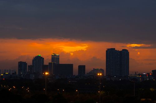 Free Beautiful city skyline silhouette at sunset with vibrant orange and dark clouds, creating an atmospheric urban scene. Stock Photo